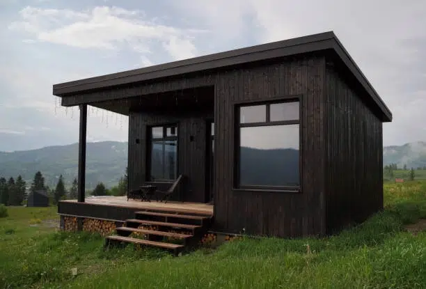 Dark wood ADU with covered porch, large windows, mountain view. -adu floor plan